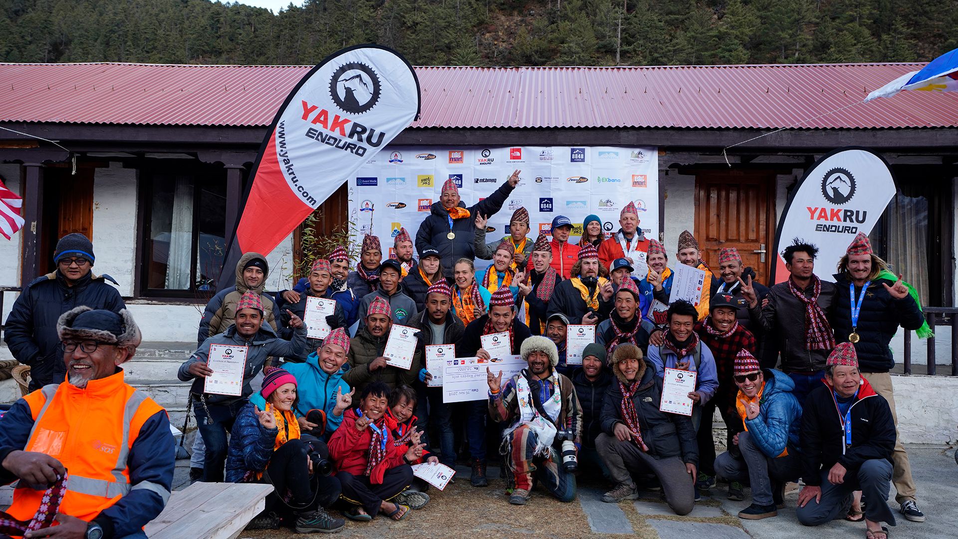 Riders, crew and locals posing together with certificates