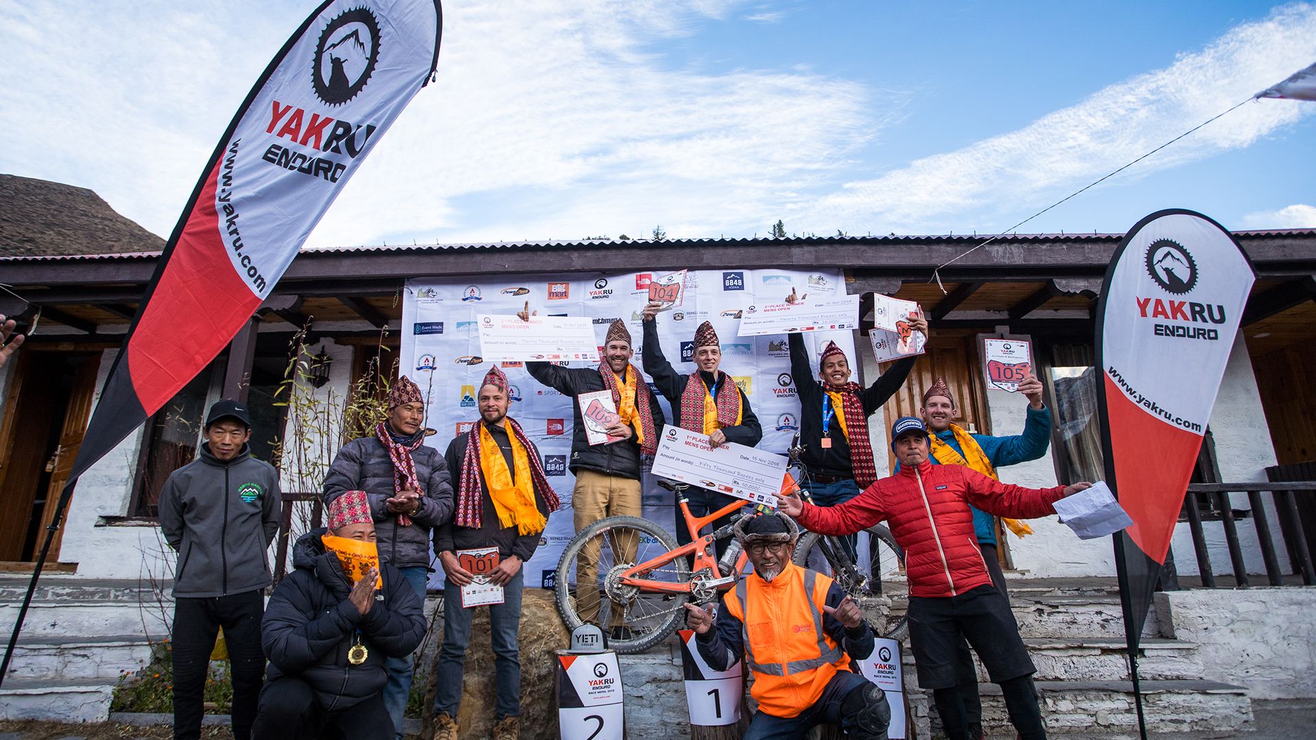Winners celebrating on the podium with ceremonial scarves